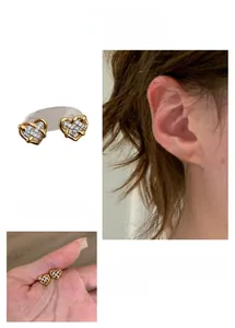 Detail of gold heart-shaped hollow earrings with glittering zircons in French style