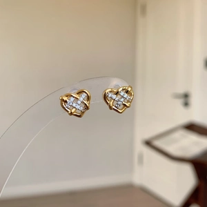 Elegant gold heart-shaped stud earrings with intricate woven crystal design and silicone backs