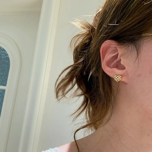 Fashionable golden heart-shaped hollow woven stud earrings with crystals on female model