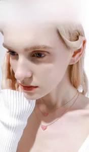 Close-up of model wearing double-layer rose gold necklace with pink heart pendants