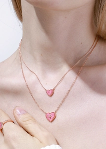 Macro detail of rose gold layered necklace with pink heart charms and star motif