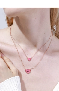 Detail of rose gold double-layered necklace with pink heart pendants and bead edges