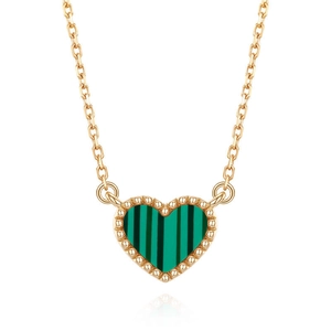 Macro detail of gold-plated heart pendant with green shell inlay and beaded edges