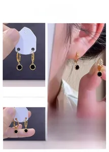 Detail of French vintage gold earrings with black round enamel pendants on a model
