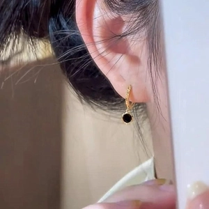 French vintage style golden hoop earrings with round black pendant on a female model