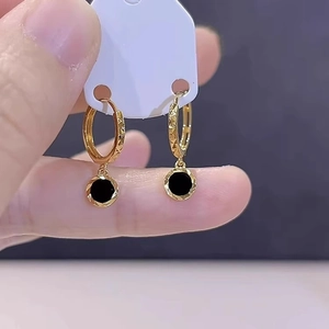 Elegant gold-tone hoop earrings with black round charms and textured diamond-cut finish