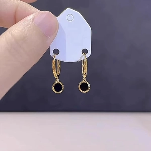 Elegant gold hoop earrings with textured diamond patterns and black round charms