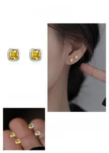 Close-up of minimalist yellow sugar cube stud earrings with sparkling crystal center