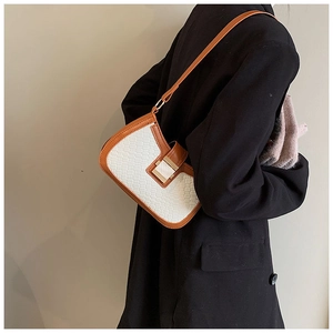 Close-up of white woven texture shoulder bag with brown leather trim and metal clasp