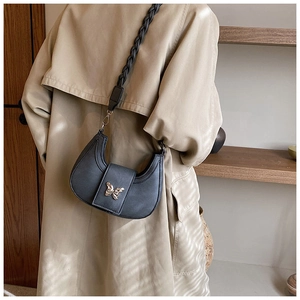 Detail of grey crescent underarm bag with gold butterfly clasp and woven strap