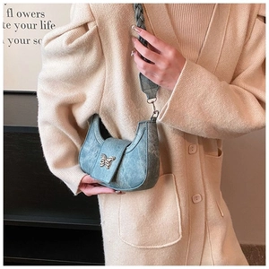 Close-up of blue crescent moon shoulder bag with butterfly buckle and woven strap