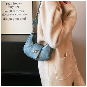 Detail of blue denim hobo bag with silver butterfly buckle and braided strap detail