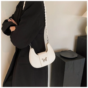 Detail of white crescent bag featuring silver butterfly buckle and braided strap