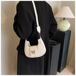 Close-up of cream crescent shoulder bag with metallic butterfly and braided strap