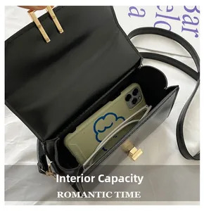 Internal capacity of black crossbody bag showing smartphone and glasses on white background