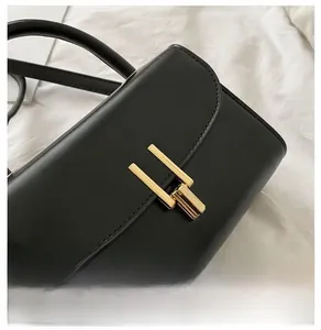 Detail of minimalist black leather handbag with premium rectangular golden metal clasp