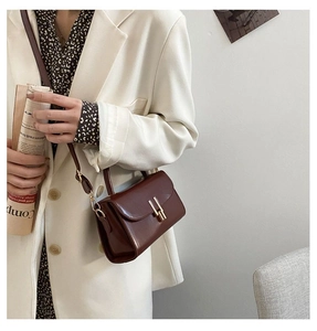 Detail of vintage reddish brown leather crossbody bag with elegant gold buckle hardware
