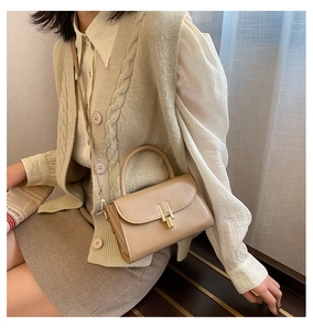 Detail view of beige leather crossbody bag with elegant gold H buckle and top handle