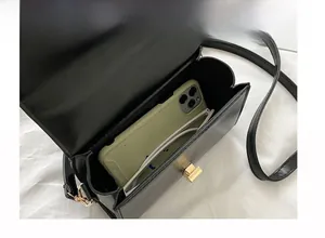 Detail view of the black leather crossbody bag interior with gold buckle and smartphone storage