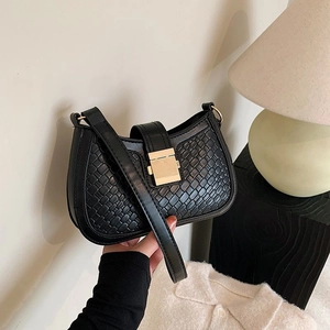 Elegant black woven crescent shoulder bag with gold buckle in a modern lifestyle setting