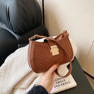 Brown woven shoulder bag with gold metal buckle in a stylish lifestyle setting