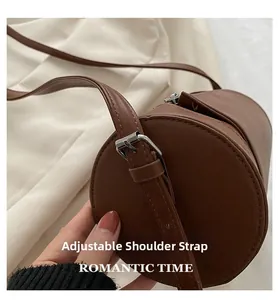Detail view of adjustable strap with silver buckle on brown vintage cylindrical bag