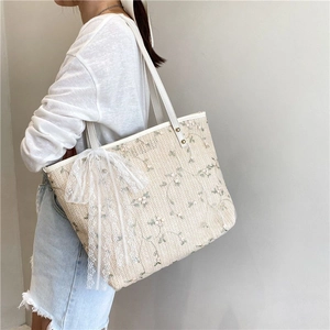 Floral embroidered straw tote bag with white lace bow and leather shoulder straps