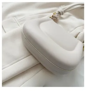 Detailed side view of cream white structured shoulder bag with premium gold metal hardware