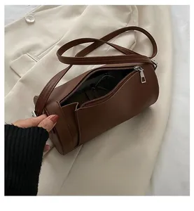 Detail view of the spacious interior of a brown cylindrical crossbody bag with accessories
