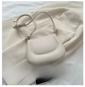 Detailed overhead view of a cream saddle bag with knot strap detail next to a smartphone