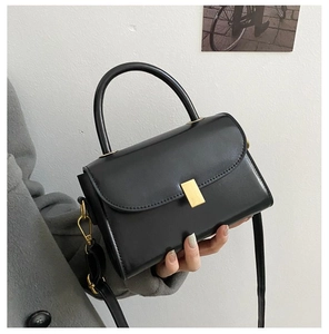 Detailed view of the black crossbody bag with gold metallic clasp and smooth finish