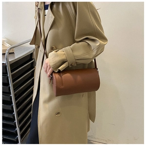Detailed close-up of brown cylindrical leather bag with precise stitching and slim strap