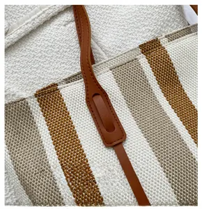 Dettaglio della cucitura della tracolla in pelle su una borsa tote a righe