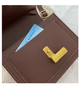 Vue détaillée du sac bandoulière en cuir marron avec poche avant et fermoir doré en forme de L