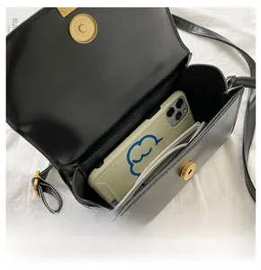 Detail view of the interior space of a black matte crossbody bag with golden magnetic clasp