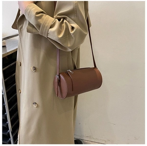 Detail of vintage brown cylindrical leather crossbody bag with minimalist shoulder strap