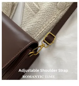 Détail de la bandoulière réglable avec boucles dorées sur le sac en cuir marron