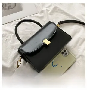 Detailed size comparison of a black mini crossbody bag with a smartphone and gold lock