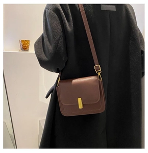 Gros plan d'un sac bandoulière vintage en cuir marron foncé avec boucle en métal doré