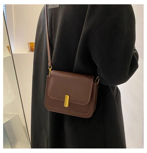 Vue détaillée du sac à bandoulière en cuir marron vintage avec boucle dorée sur le modèle