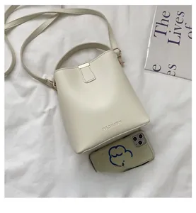 Detail of cream bucket bag with FASHION logo and size comparison with smartphone