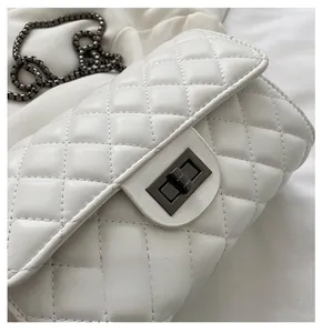 Detail of white quilted chain bag featuring dark grey metal twist lock and PU leather texture