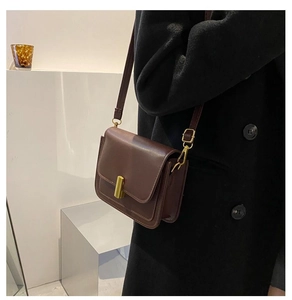 Détail du sac bandoulière en cuir marron foncé avec fermoir doré et structure à soufflet