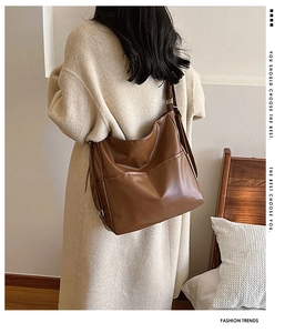 Grand sac hobo en cuir PU marron caramel porté par un mannequin sur un manteau
