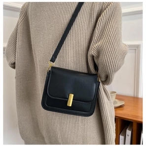 Vue détaillée du sac bandoulière en cuir noir avec boucle dorée sur un mannequin