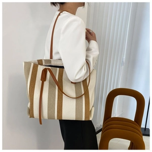 Dettaglio di una grande borsa tote in tela a righe con spallacci in pelle marrone