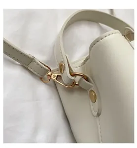 Close-up of golden metal lobster clasp and premium white PU leather strap on shoulder bag
