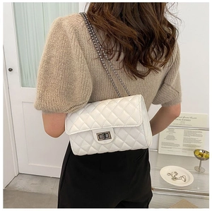 Rear view of white quilted leather flap bag with silver chain strap on model