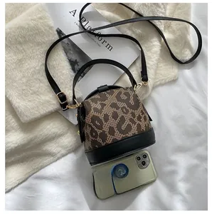 Detail view of leopard print round bag showing size comparison with a smartphone