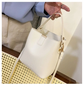 Close-up of white PU leather bucket bag with gold hardware and FASHION lettering